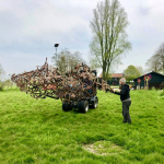 Organisator Bart Belonje ‘dirigeert’ een groot werk van Gjalt Blaauw naar zijn plek in de Beeldentuin.